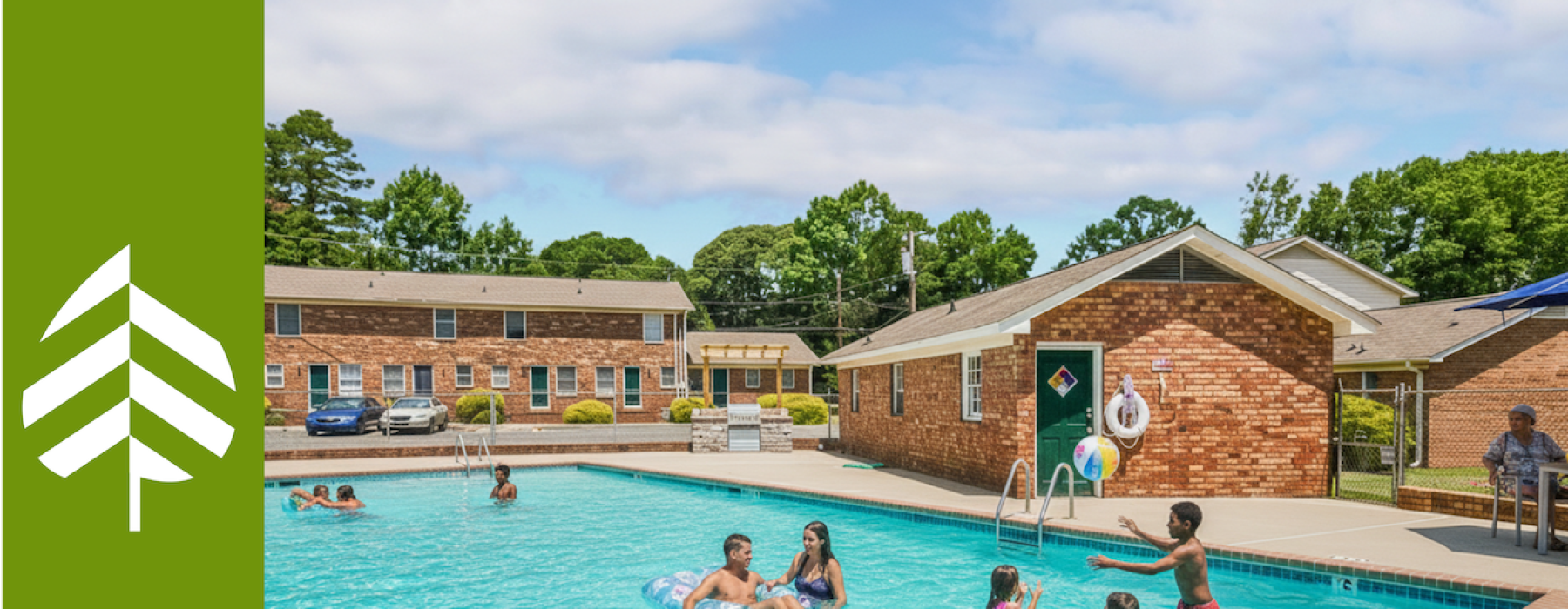Residents and families enjoying the resort-style outdoor swimming pool at Retreat at Kannapolis Apartments in Kannapolis, NC, featuring a spacious sundeck and brick clubhouse in a pet-friendly community near Downtown Kannapolis and I-85