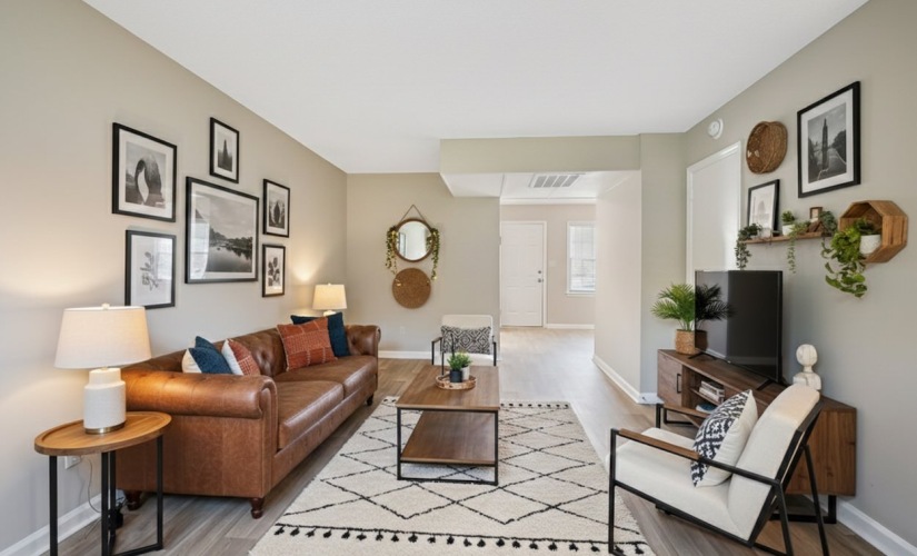 Spacious open-concept living room at Retreat at Kannapolis in Kannapolis, NC featuring wood-style flooring, neutral paint, large wall art, modern lighting, and comfortable seating in a renovated 1 or 2 bedroom apartment near Downtown Kannapolis and I-85.